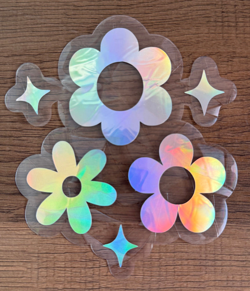 Retro daisy rainbow window cling set with three flowers and sparkle accents creating colorful prism reflections on a sunny window