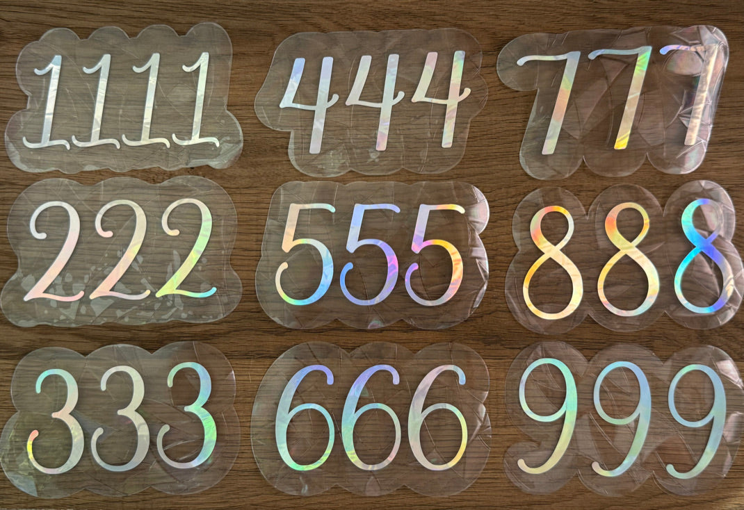 Angel number rainbow window cling displayed on a sunny window with prism reflections