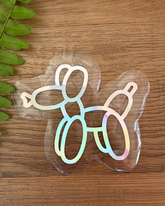 Balloon dog rainbow window cling creating colorful prism reflections on a sunny window.