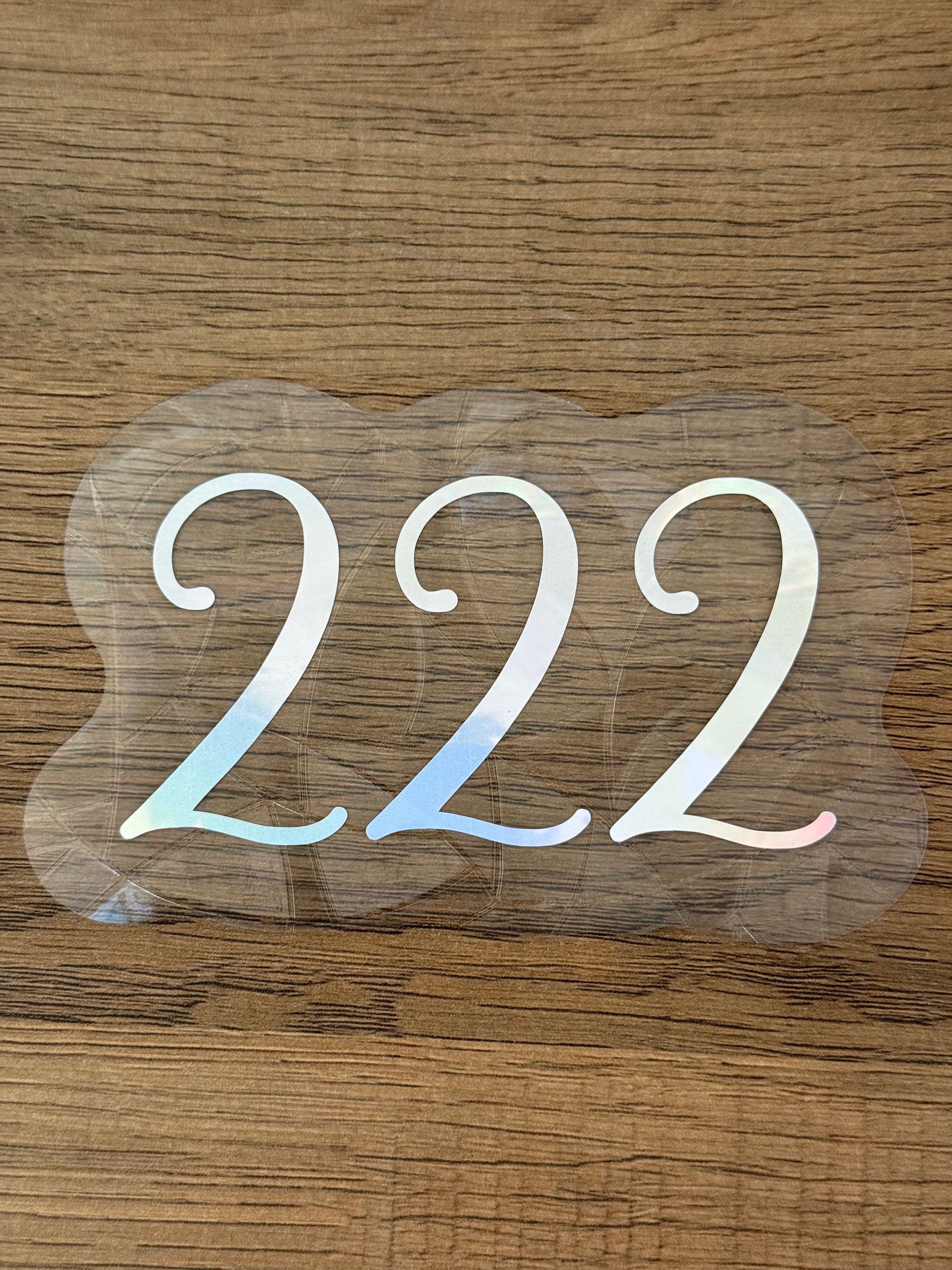 222 angel number rainbow window cling displayed on a sunny window with prism reflections