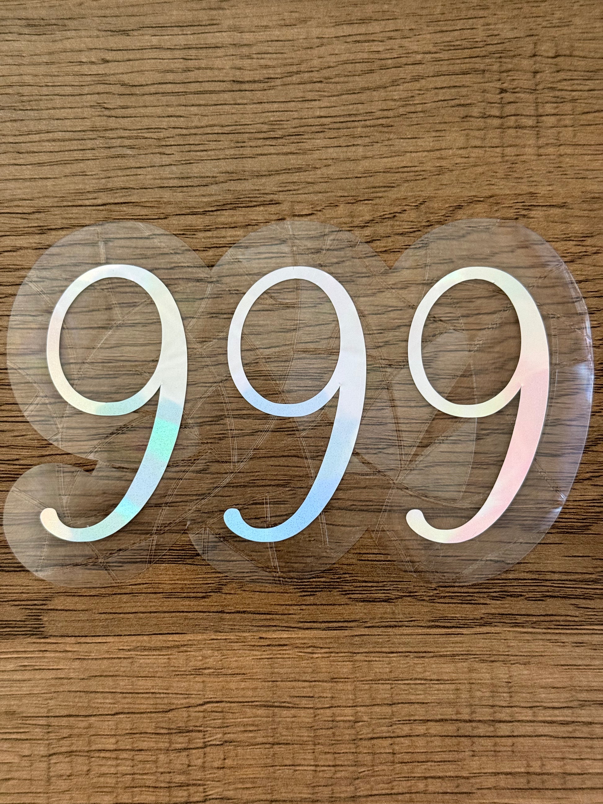 999 angel number rainbow window cling displayed on a sunny window with prism light