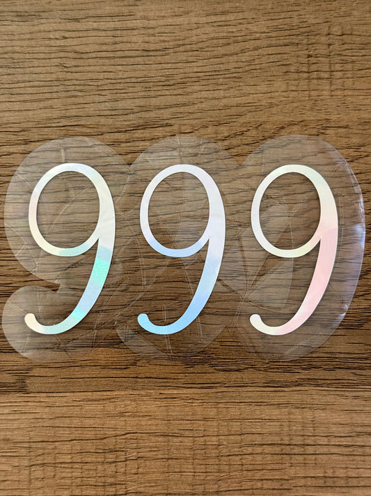 999 angel number rainbow window cling displayed on a sunny window with prism light